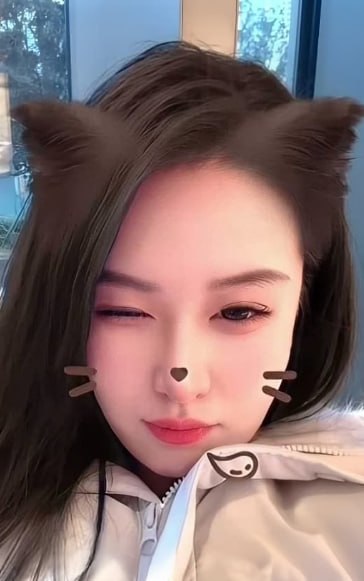 牛奶秋刀姨 穿浅色拉链外套闭一只眼，脸旁有猫耳和胡须效果