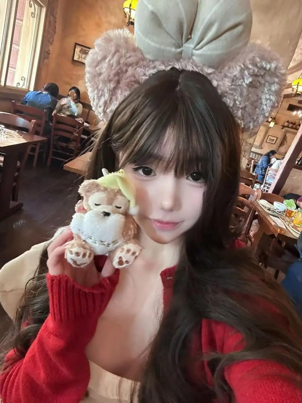 野心坏蛋毛绒发箍与红色外套近景，手持小玩偶，背景为餐厅桌椅