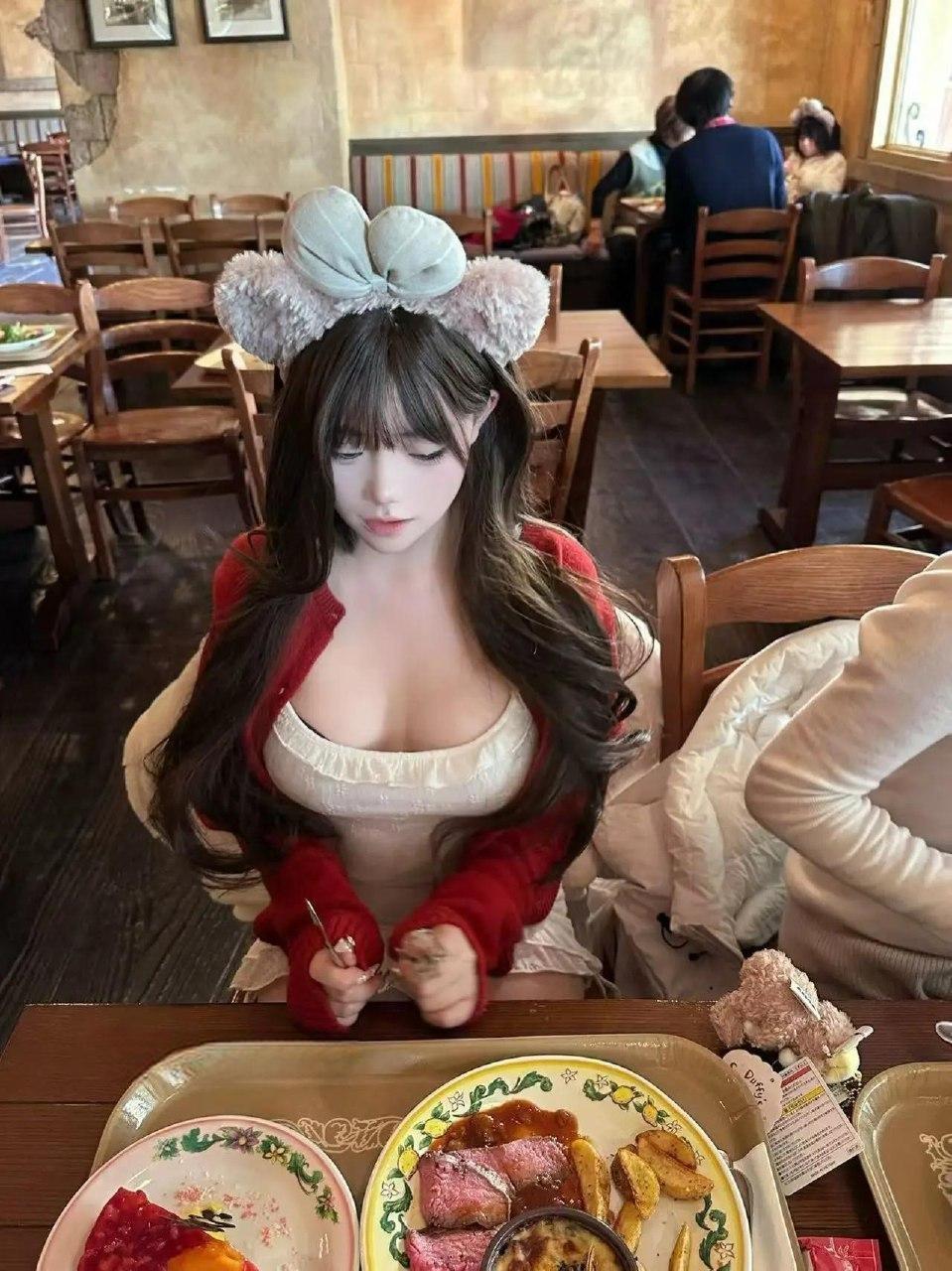 野心坏蛋餐桌前低头坐姿，毛绒发箍、红色外套与桌面餐具同框